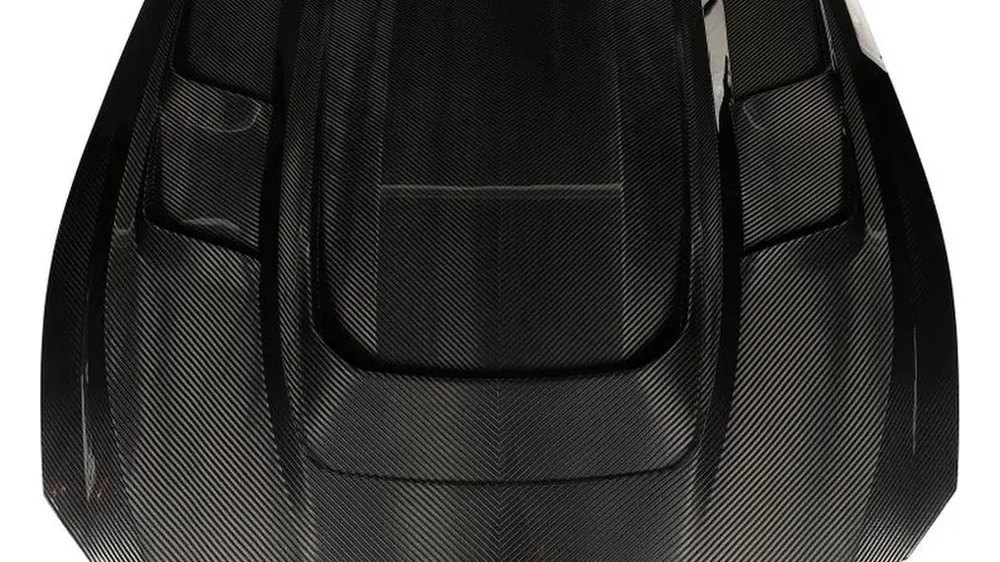 Carbon fiber hood with a central scoop and side vents, photographed on white